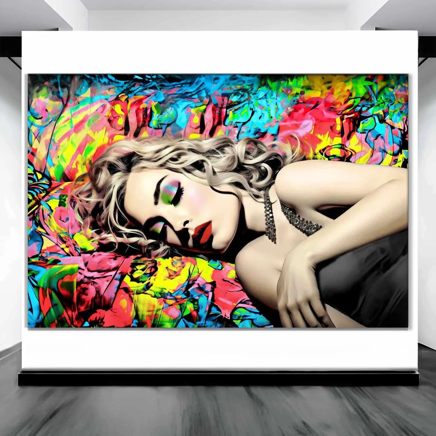 Art gallery mockup of Madonna lying down with her eyes closed in a black dress, set against a vibrant backdrop of blue, red, and yellow graffiti. Title: Graffiti Lullaby-Graphique Addictions.