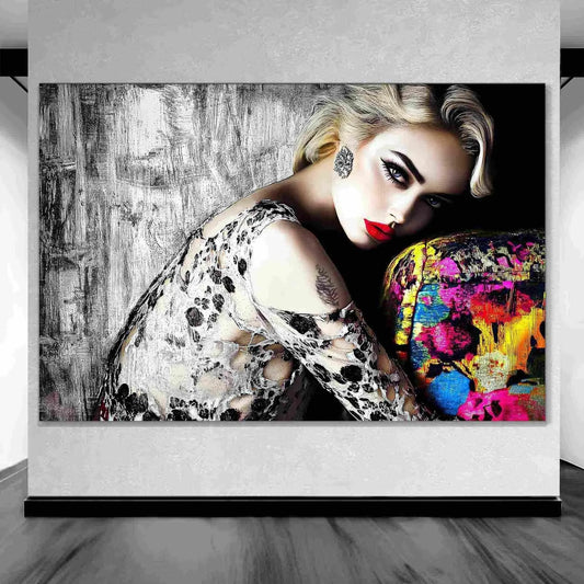 Art gallery display of blonde model with bold red lips, wearing a black-and-white lace dress, leaning against a colorful sofa with a textured black-and-white wall in the background. Red Lips and Lace-Graphique Addictions.
