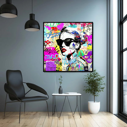 Foyer wall art of a woman wearing sunglasses with tattoos on her body and face. Surrounded by street-style stickers, labels, numbers, letters, and symbols in vibrant colors. Titled: Graffiti Chic Chronicles-Graphique Addictions.